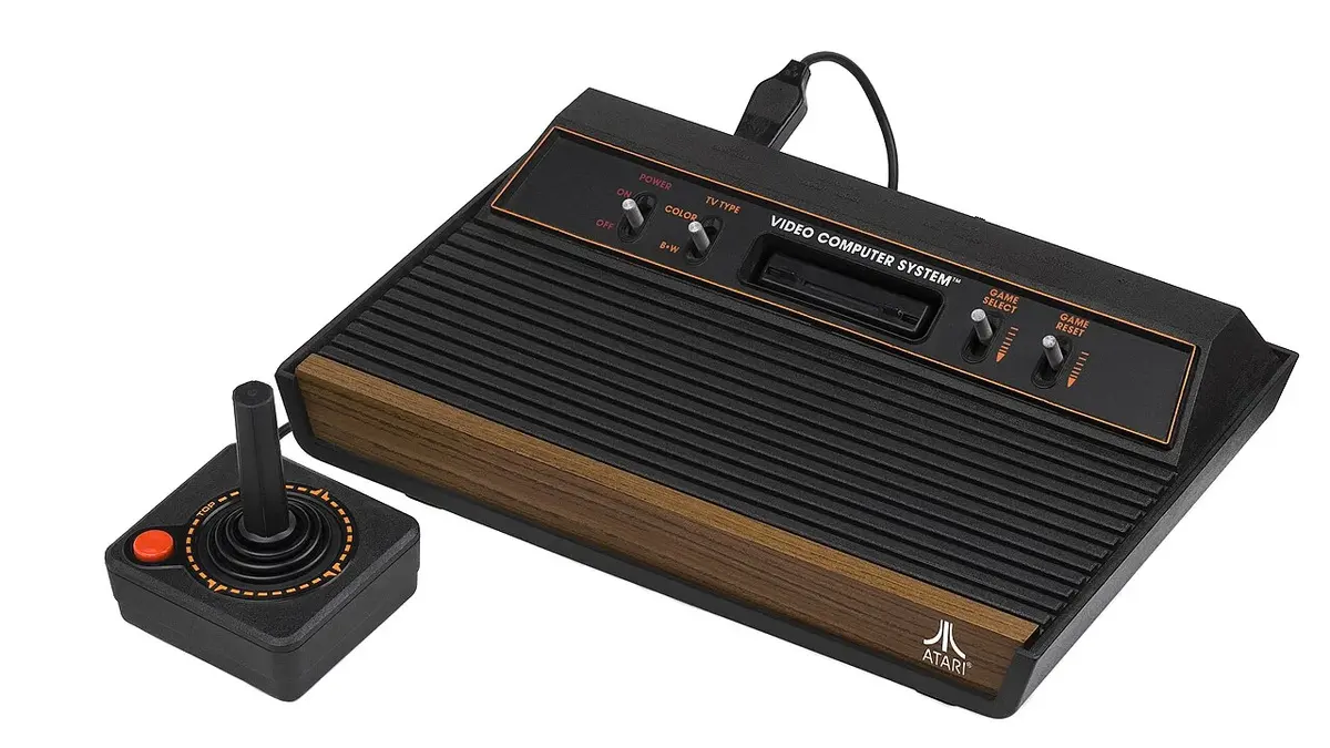 Atari 2600 nero con finitura effetto legno, quattro interruttori e joystick.