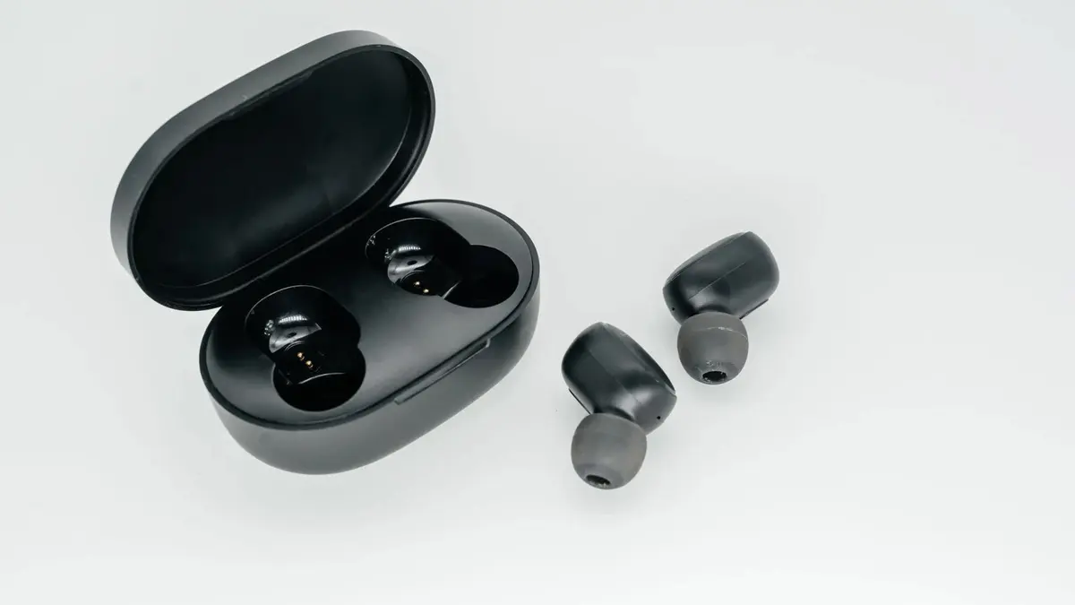 Auricolari wireless neri accanto alla custodia aperta.