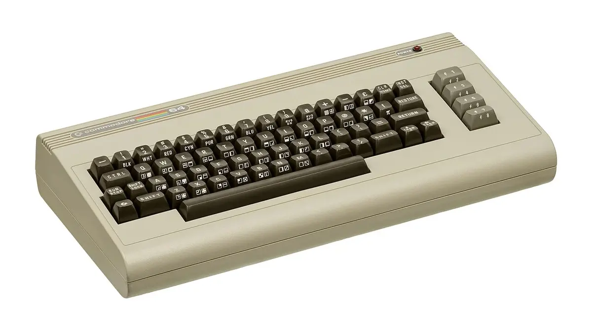 Commodore 64 beige con tastiera scura, fotografato su fondo bianco.