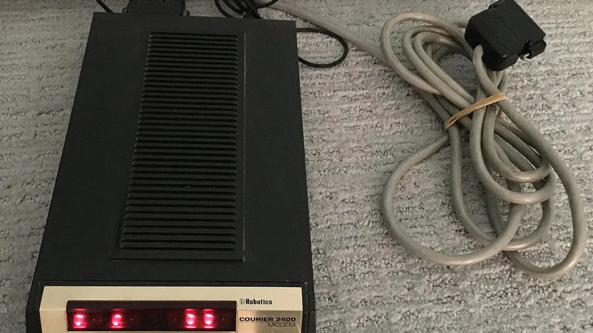 Modem esterno USRobotics Courier 2400 acceso, con spie e cavo seriale.